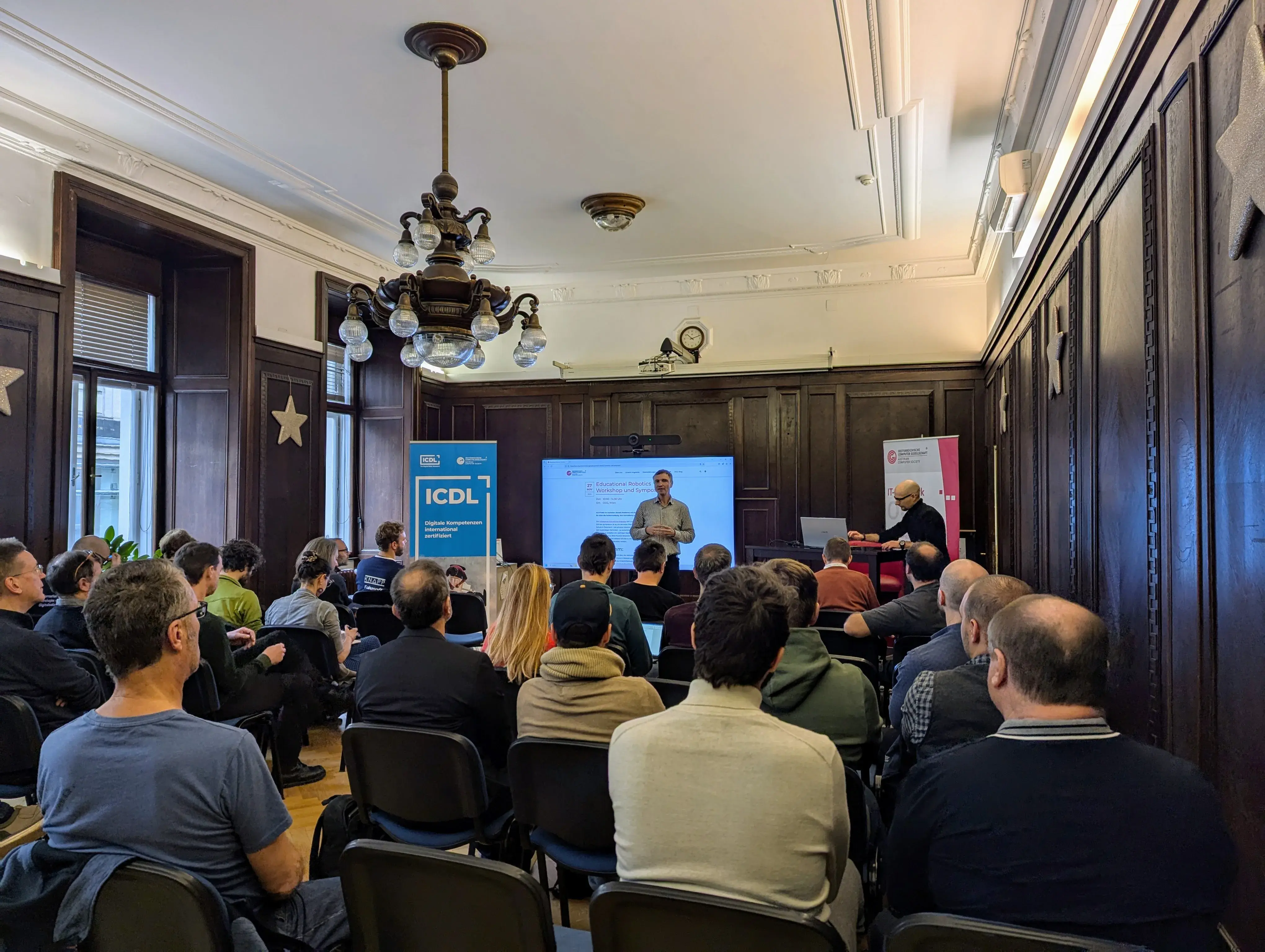 Ronald Bieber begrüßt die Teilnehmer*innen des Symposiums Educational Robotic im Heinz Zemanek Saal der OCG