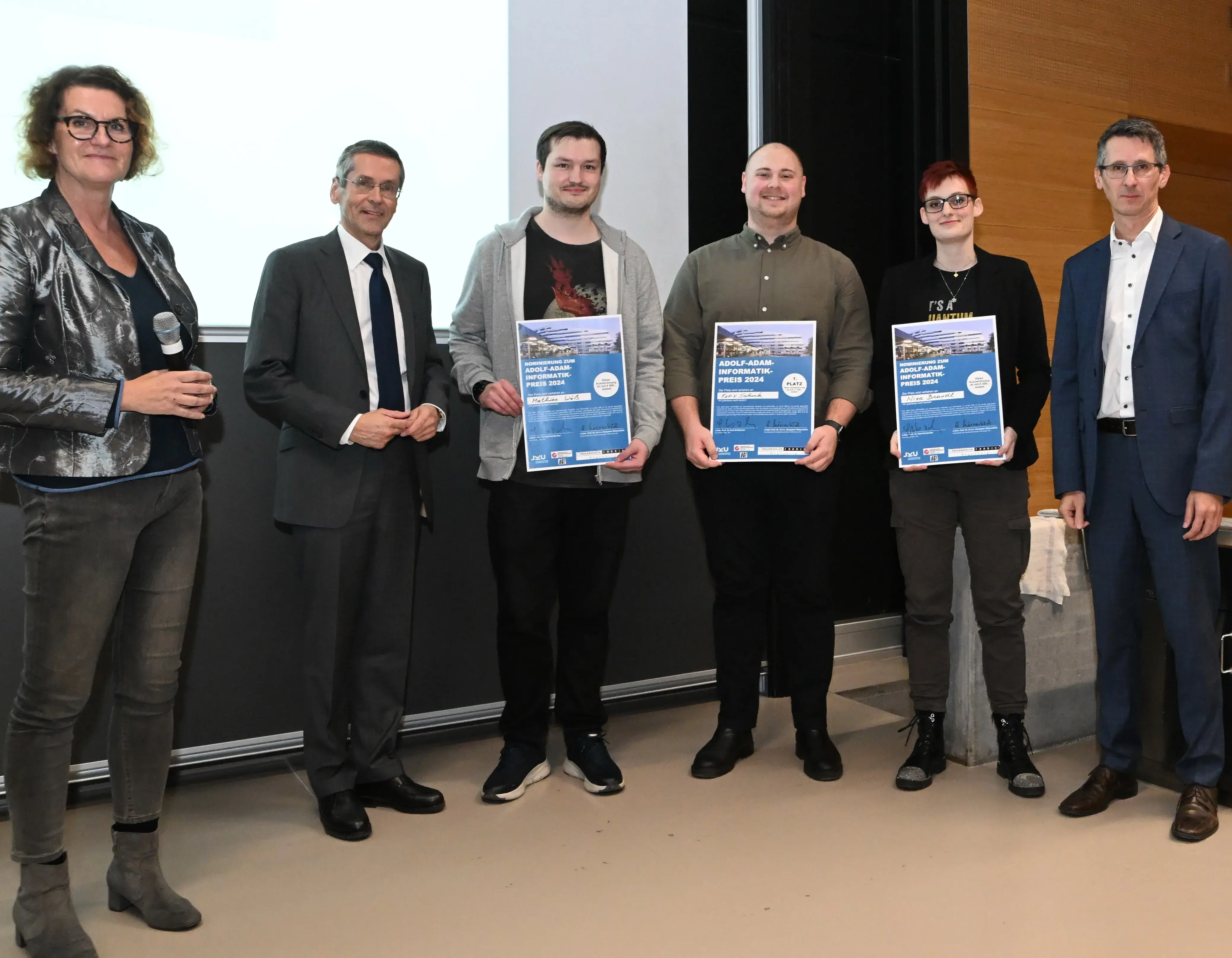 Gabriele Kotsis, Wilfried Seyruck und die Finalist*innen: Den ersten Platz erreichte Felix Schenk (Mitte), den zweiten Platz Nina Brandl (rechts) und den dritten Platz Mathias Wöß (links) und Hanspeter Mösenböck ganz links.