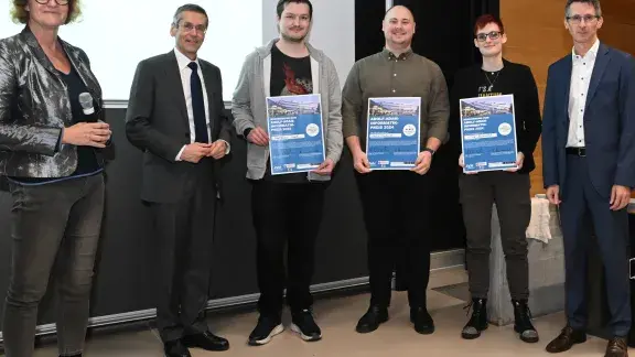 Gabriele Kotsis, Wilfried Seyruck und die Finalist*innen: Den ersten Platz erreichte Felix Schenk (Mitte), den zweiten Platz Nina Brandl (rechts) und den dritten Platz Mathias Wöß (links) und Hanspeter Mösenböck ganz links.